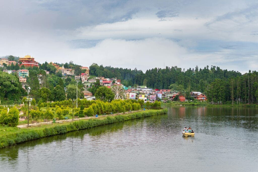 A picturesque view of Mirik, West Bengal, with colorful buildings, lush greenery, and serene Sumendu Lake.