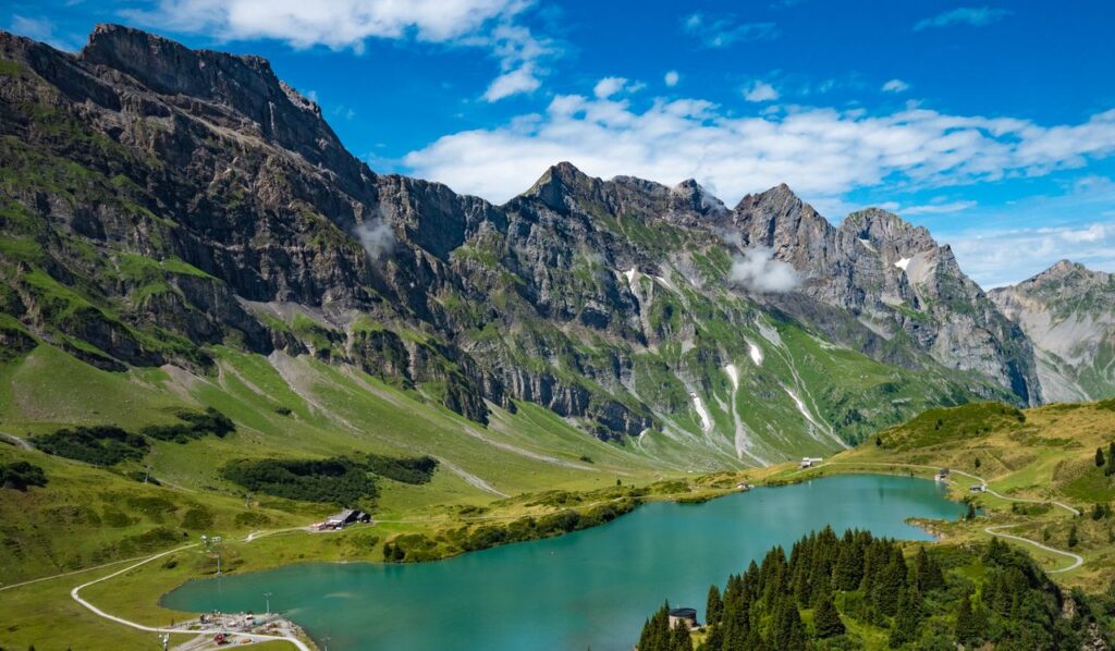 A stunning aerial view of the Swiss Alps featuring a serene blue lake and lush green landscape.