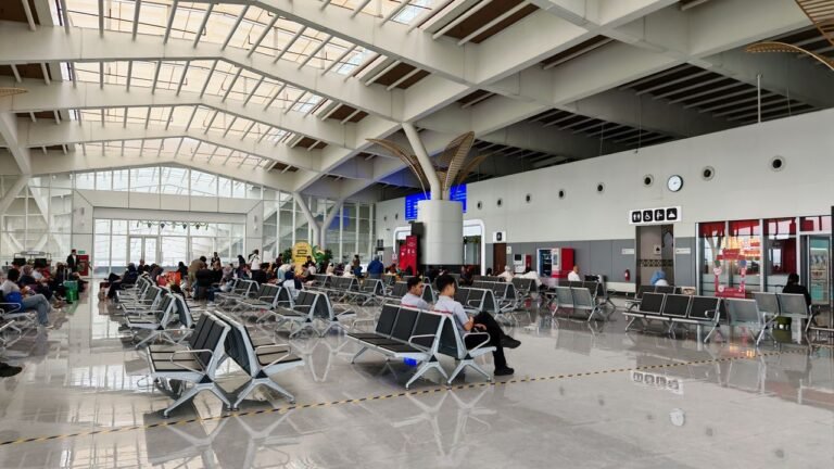 A bustling airport lounge with modern seating and passengers waiting.