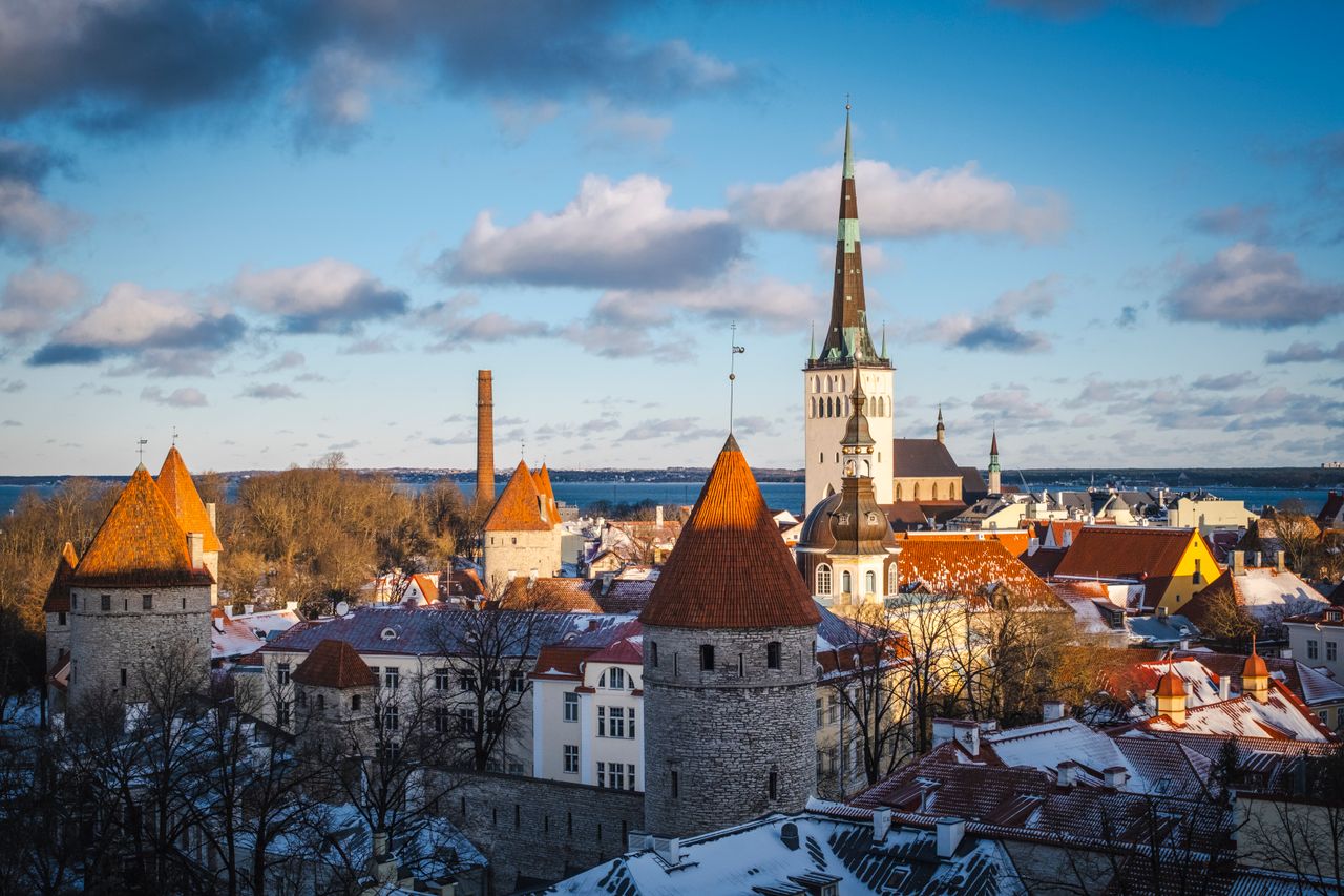 Scenic winterscape of Tallinn Old Town featuring St. Olaf's Church and medieval towers under a bright sky.