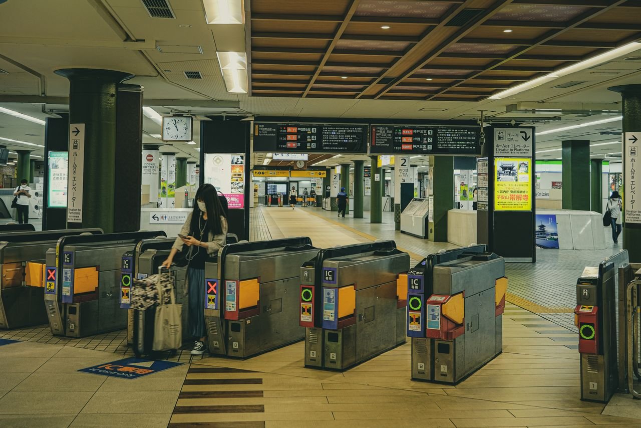 A Japanese railway station in Nara featuring ticket gates and travelers, illustrating urban transit life.